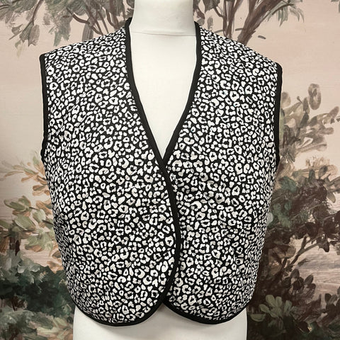 Black and white leopard print vest on a mannequin against a floral background