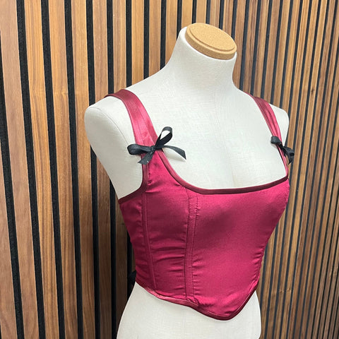 Pink corset top on a mannequin against a wooden slat background made at TMS