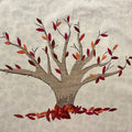 Embroidered tree with autumn leaves on a textured fabric background at TMS