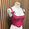 Pink corset top on a mannequin against a wooden slat background made at TMS