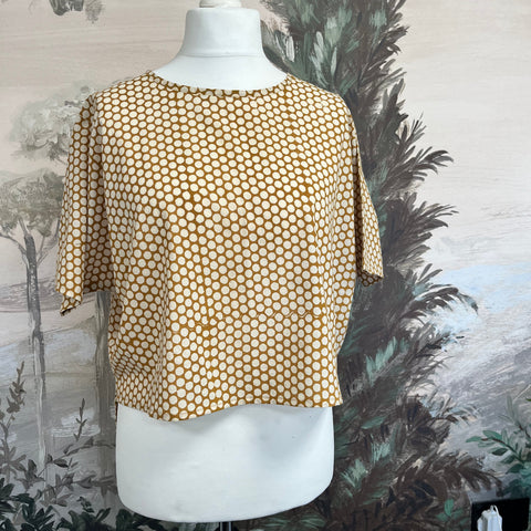 Mannequin wearing a gold patterned garment with a decorative background made at TMS