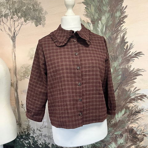 Brown plaid shirt on a mannequin against a decorative background made at TMS
